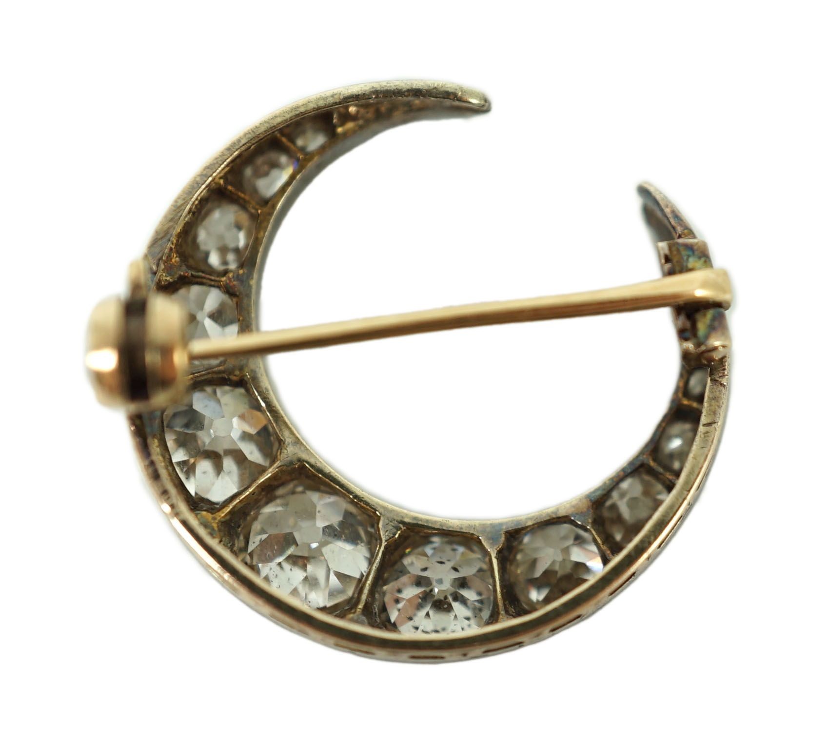 A Victorian gold, silver and graduated thirteen stone diamond set crescent brooch